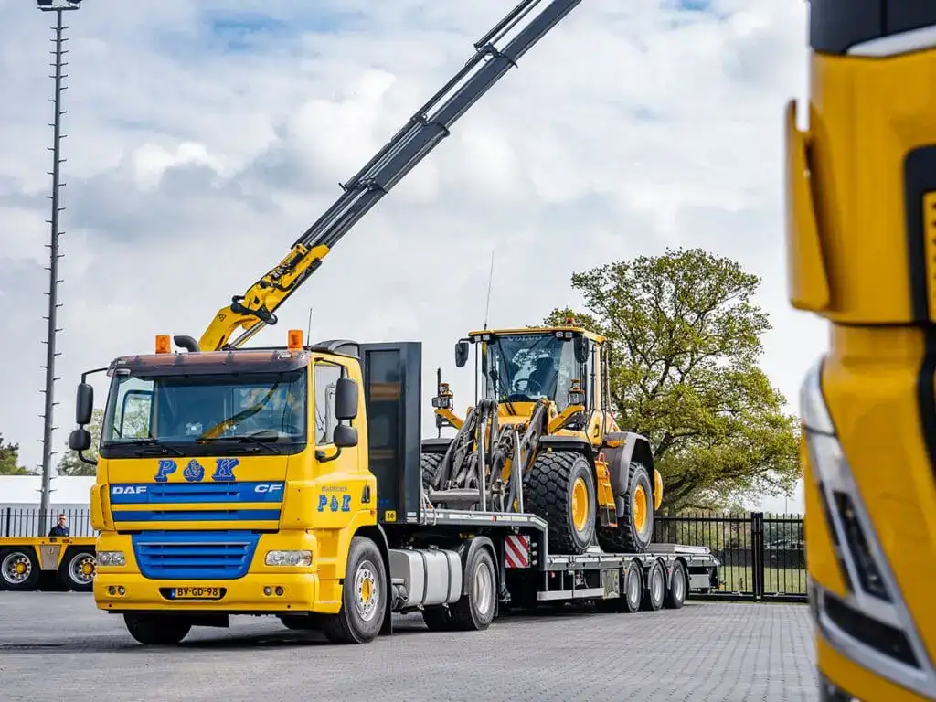 Vrachtwagen van P&K met een shovel op de dieplader