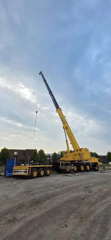 Uitgeschoven telescoopgiek met hijshaak tegen een bewolkte lucht