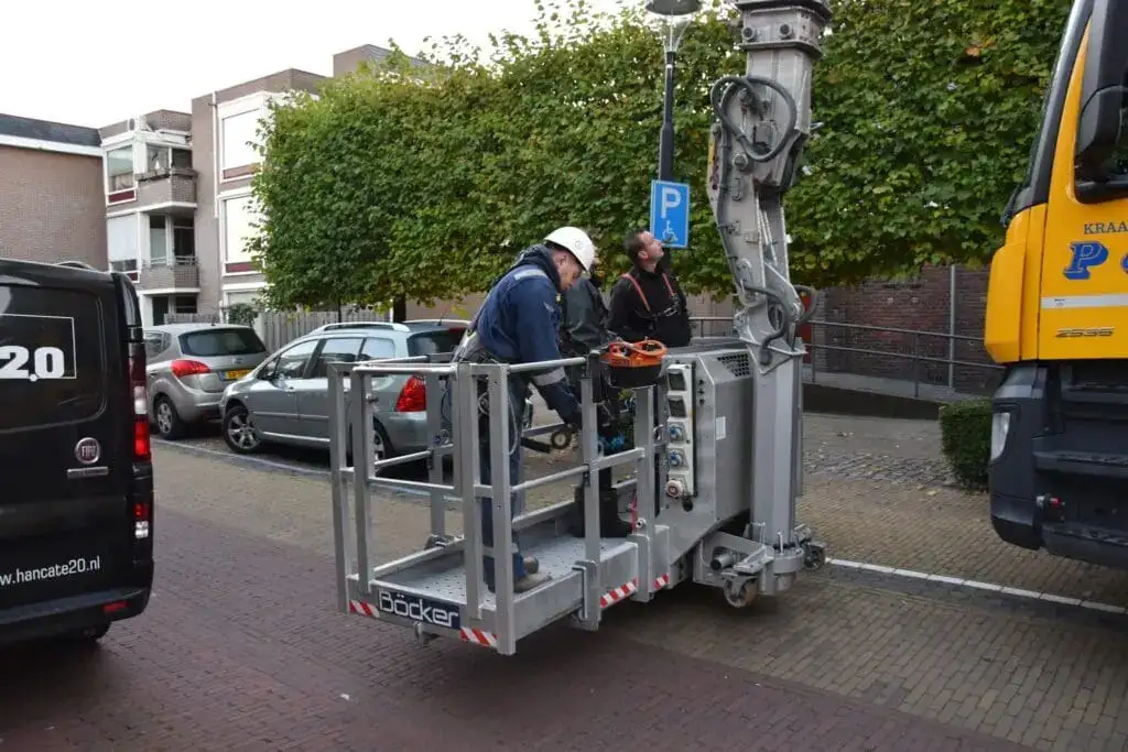 Twee monteurs in de personenbak van de autokraan bij een gevel