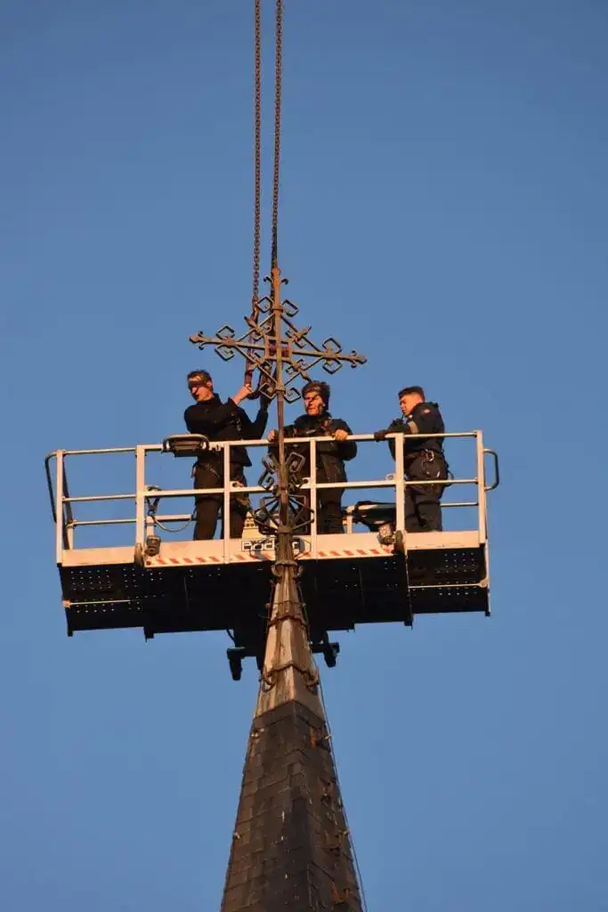 Monteurs in de personenbak van de autokraan bij een kerktoren