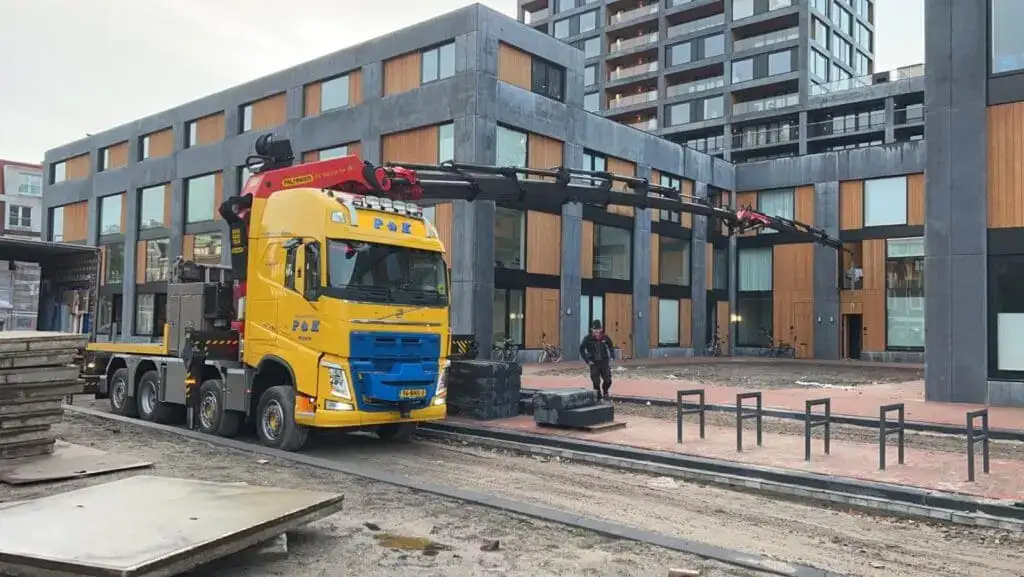Vrachtwagen met autolaadkraan voor een appartementengebouw