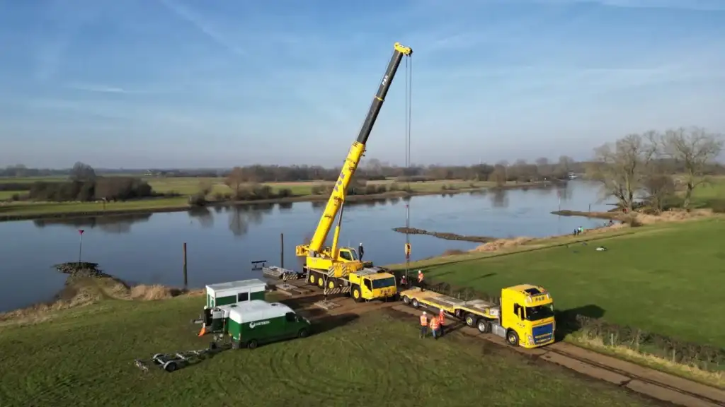 Mobiele kraan van P&K Kranen tijdens een hijsklus aan de waterkant