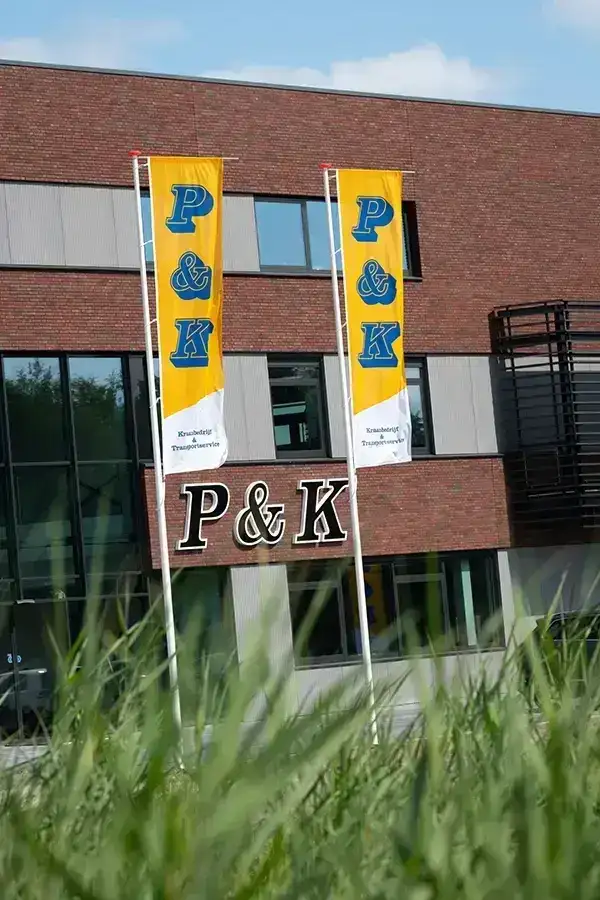 bedrijfspand van P&K Kranen in Enter met vlaggen