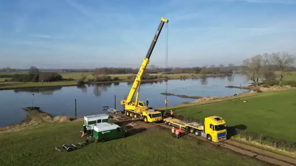 mobiele kraan op rijplaten langs de rivier