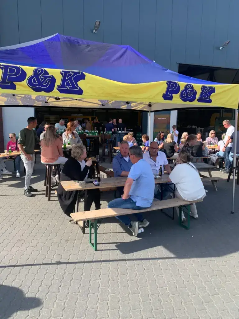 Gasten aan picknicktafels onder de P&K-partytent op de familiedag