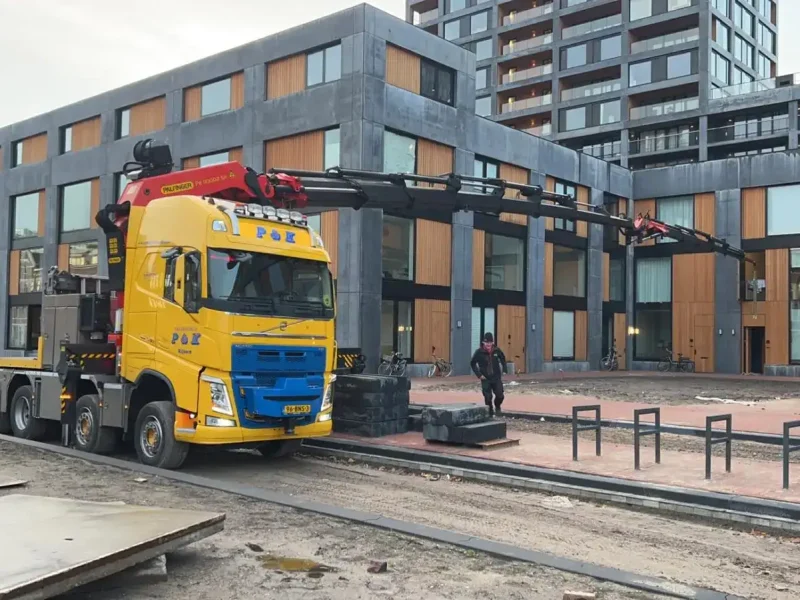Vrachtwagen met autolaadkraan voor een appartementengebouw