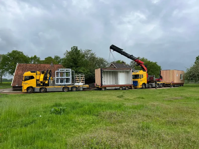 Kozijn dat met de autolaadkraan naar een woning wordt getild