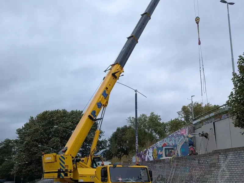 Mobiele telescoopkraan van P&K hijst een prefab wand op de Rijnkade