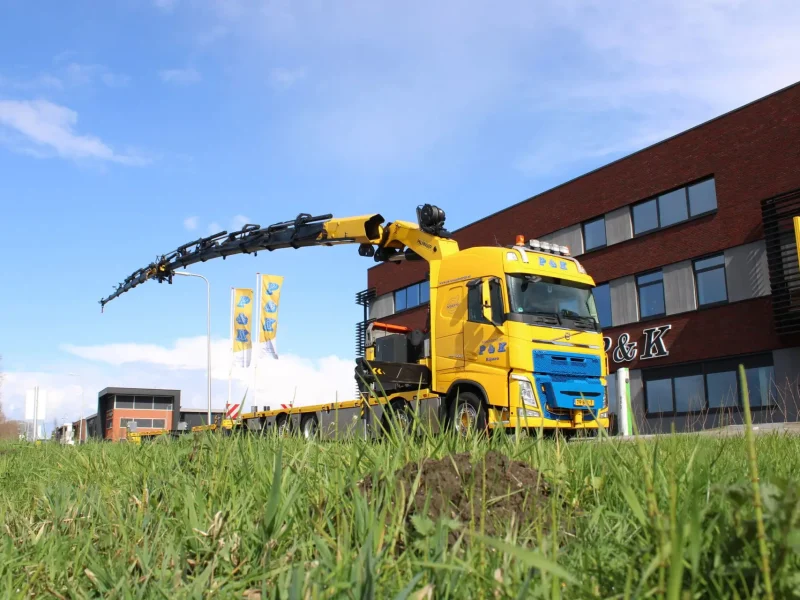 Autolaadkraan van P&K voor het bedrijfspand met mooi weer op de achtergrond