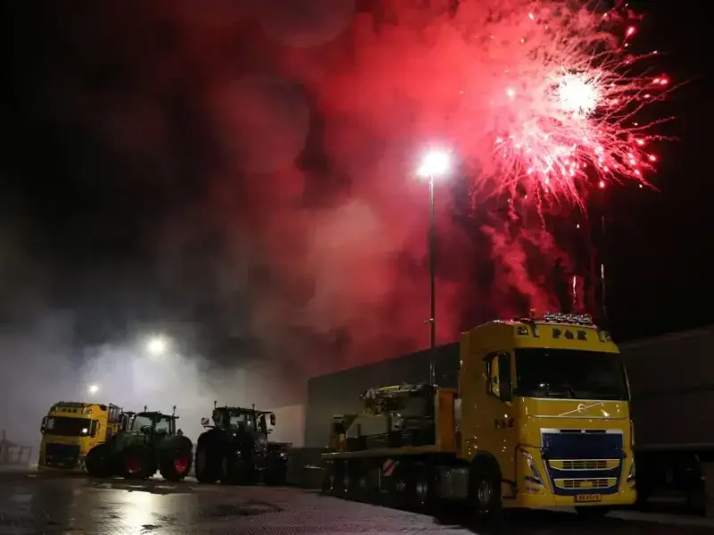 Vrachtwagens van P&K met vuurwerk op de achtergrond bij de levering van de Sany-rupskraan