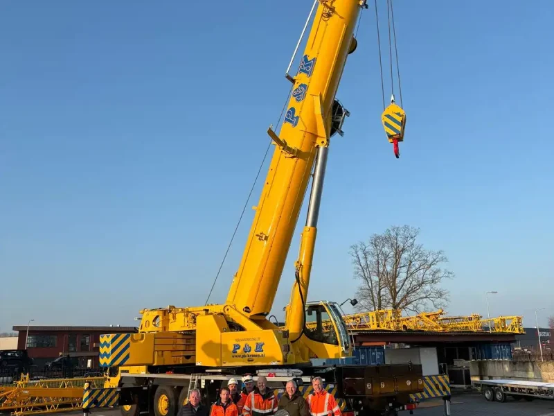 Giek en hijshaak van een mobiele kraan tegen een blauwe lucht