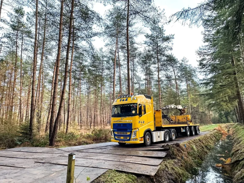 Vrachtwagen van P&K met rijplaten op een bospad