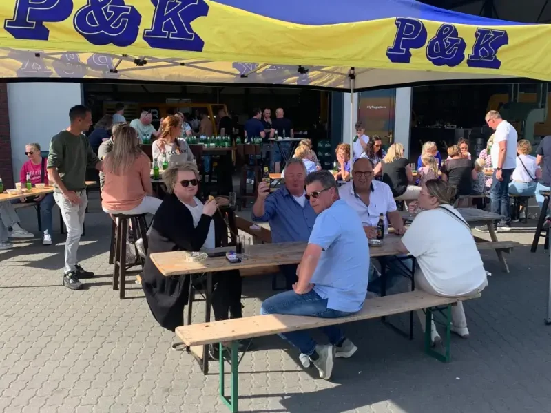 Gasten aan picknicktafels onder de P&K-partytent op de familiedag
