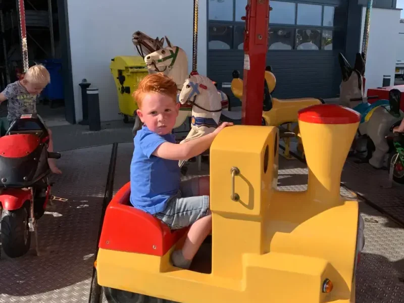 Kind op een speelgoedgraafmachine tijdens de familiedag van P&K