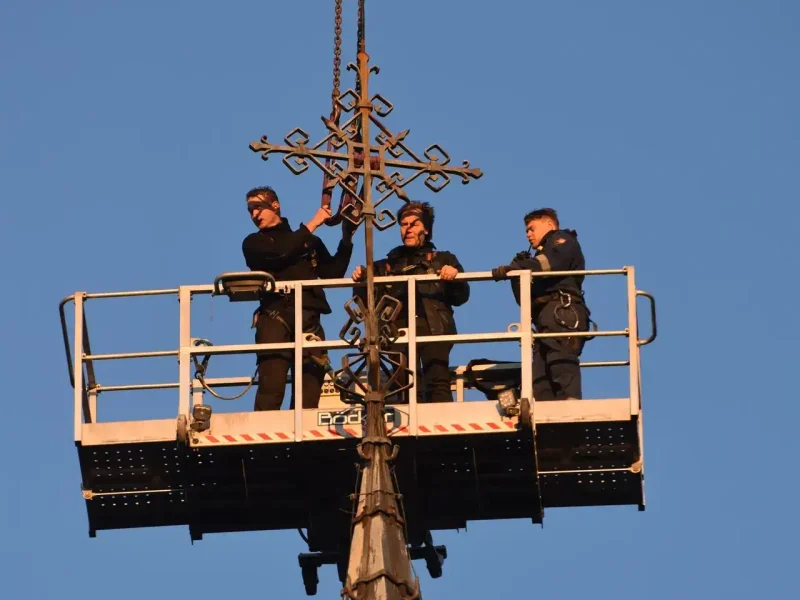 Monteurs in de personenbak van de autokraan bij een kerktoren