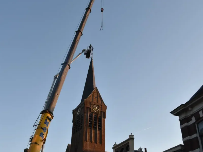 Autokraan van P&K met personenbak naast de kerktoren in Rijssen